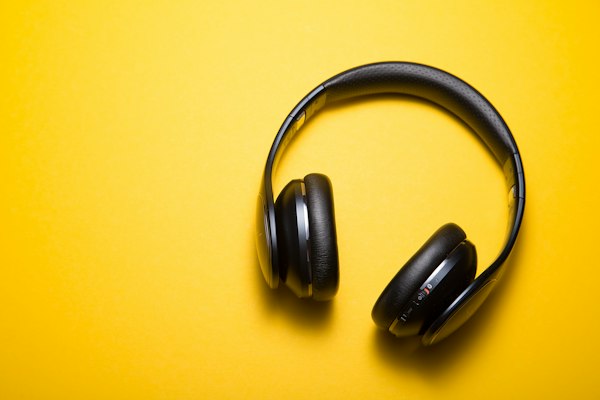 Fone de ouvido preto sobre uma superfície escura, mostrando o acabamento do produto